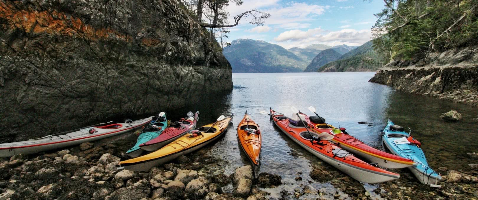 Kayaks floating in a calm bay on on of our sea kayak expeditions