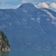 A kayaker appears tiny as she paddles into the awesome mountain scenery of Toba Inlet
