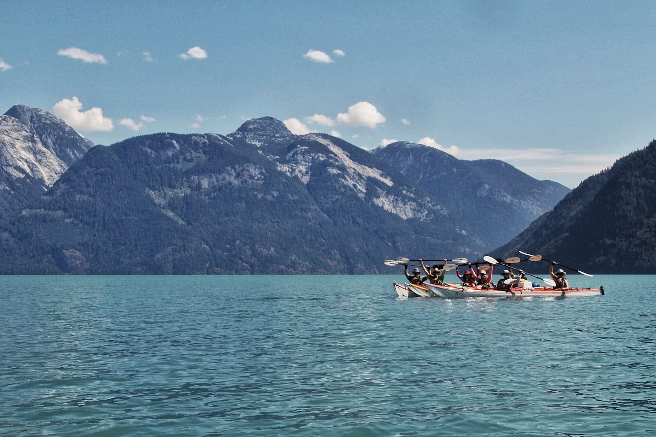 A group of kayakers on a Desolation & Mountains tour pose for a group photo in Toba Inlet