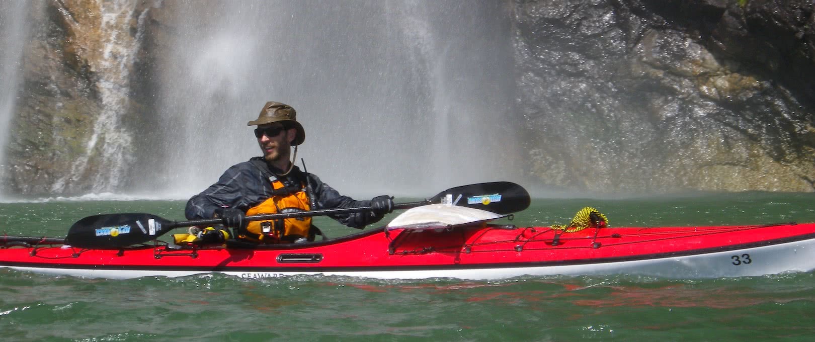 man in red kayak near waterfall