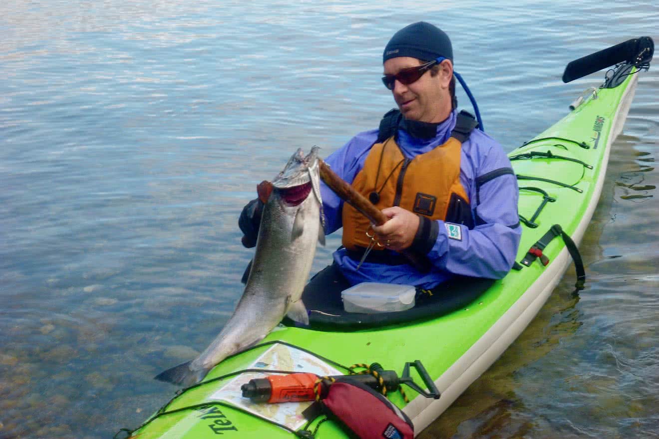 A guest after a successful catch of Salmon from a kayak in Desolation Sound