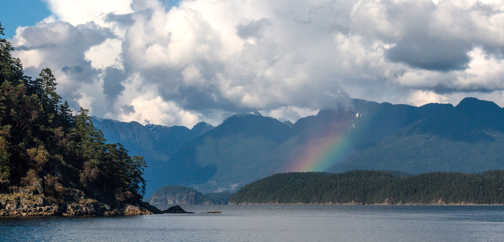 A rainbow and big white clouds over Mink Island in Desolation Sound
