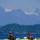 A double kayak in the foreground and the snow capped peaks of Mount Denman and the Coast mountains behind