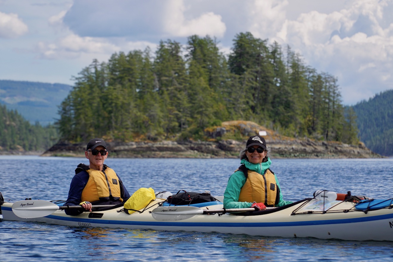 Two paddlers in a double kayak posing for a photo in Malaspina Inlet on one of our kayak tours