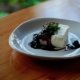 A dish of tiramisu and ice cream with a blueberry sauce