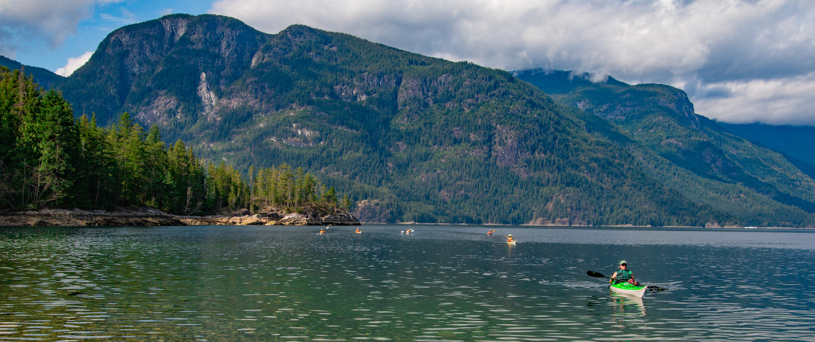 A group of kayakers on one of our sea kayak expeditions approaches a beach for a break during their day on the water