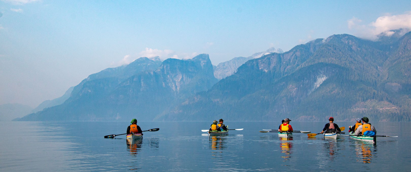 group of kayakers facing mountaint