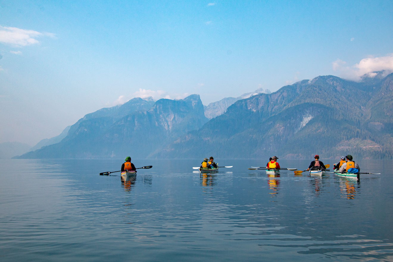 group of kayakers facing the mountain